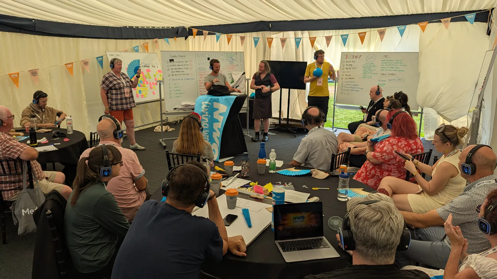 The Fans for Life 2 design sprint under way in a marquee at the Northumbrian Water Innovation Festival, customers seated around tables in headphones while facilitators work at whiteboards